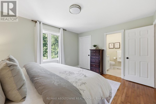 Bedroom with king size bed, dark wood dresser, and ensuite bathroom - 437 Cairncroft Road Oakville