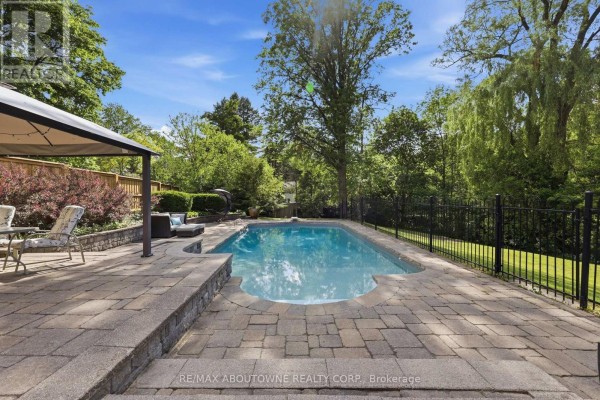 Inground pool with stone patio, outdoor seating, and canopy - 437 Cairncroft Road Oakville