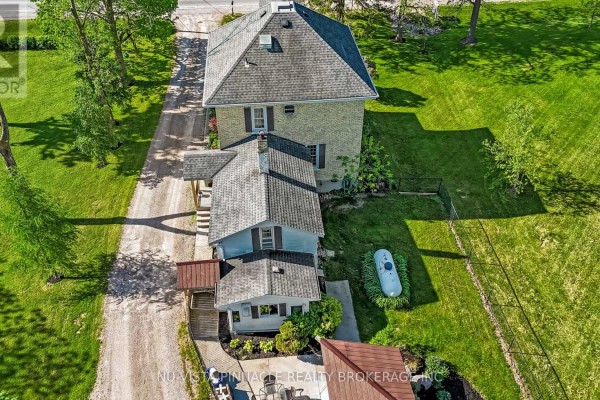 Exterior view of white barns with a large red shipping container and a fence. - 4378 Mcgillivray Drive W, North Middlesex
