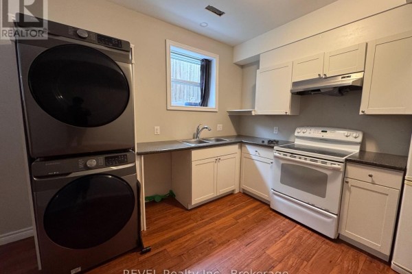 View of the open-concept living area, dining space, and kitchen with dark wood floors. - 438 Mcalpine Avenue N, Welland