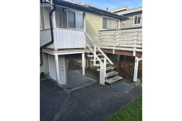 Stairs leading to a deck above a basement entrance, with concrete flooring. - 4386 Oxford Street, Burnaby