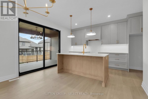 Modern kitchen with island, grey cabinets, gold faucet, and deck access - 4387 Green Bend Road London South