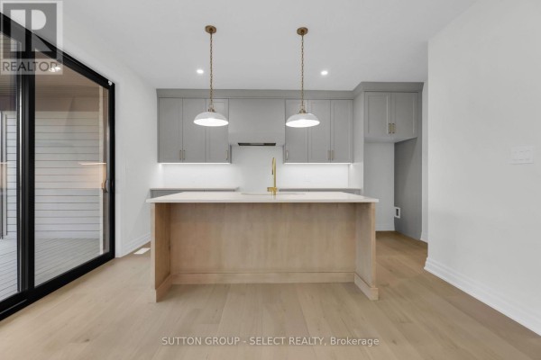 Modern kitchen with island, grey cabinets, gold faucet, and sliding glass door - 4387 Green Bend Road London South