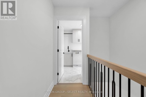 Hallway overlooking a modern laundry room with white cabinets and marble floors - 4387 Green Bend Road London South