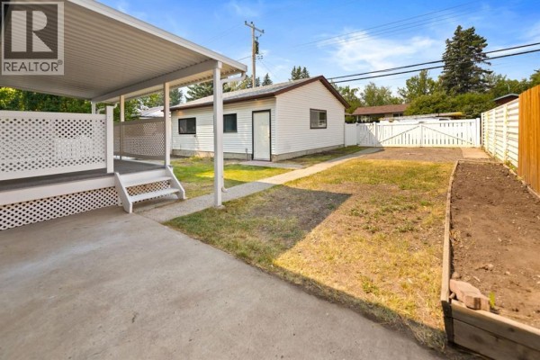 Backyard view with a covered deck, detached garage, and fenced yard. - 439 Arlington Drive Se, Calgary