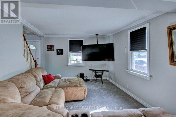 Living room with a beige sectional sofa, mounted television, and grey carpet. - 439 Beatrice Street, London East