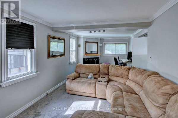 Living room with a beige sectional sofa and a view into a connected dining or office area. - 439 Beatrice Street, London East