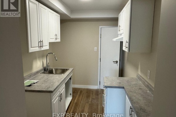 Small kitchen with white cabinets, gray countertops, and stainless steel sink. - 439 Main Street E, North Bay