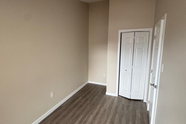 Empty room with beige walls, white double doors, and wood-look flooring. - 439 Main Street E, North Bay