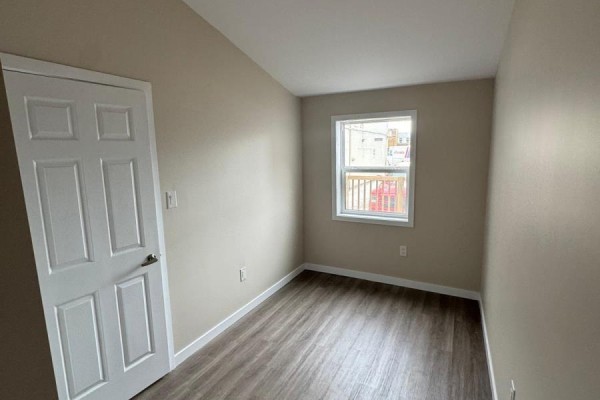 Empty room with beige walls, white door, and a window with a view. - 439 Main Street E, North Bay