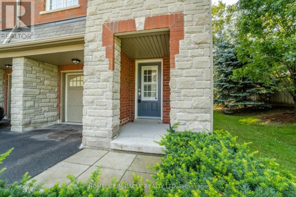 Close-up of townhouse entrance door with stone facade and surrounding greenery. - 44 - 1701 Finch Avenue, Pickering
