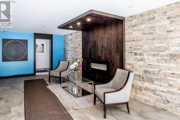 Lobby seating area with two grey chairs, glass table, and modern fireplace. - 44 - 51 Broadfield Drive, Toronto