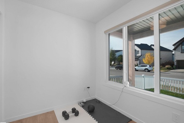 Interior room with large windows overlooking a street, featuring dumbbells and a yoga mat. - #44 1025 Secord Promenade Pm Nw, Edmonton