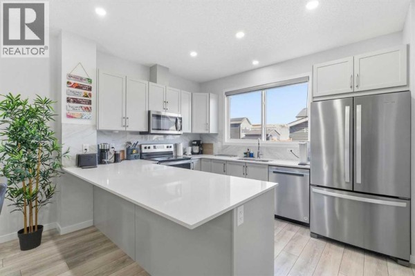 Living room with a large sectional sofa, grey coffee table, and entertainment unit with a TV. - 44 Amblefield Avenue Nw, Calgary