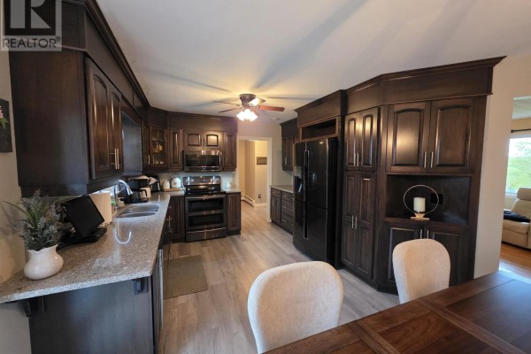 Wide view of the kitchen and dining area showing dark wood cabinets and appliances. - 44 Beaumont Avenue, Sydney River