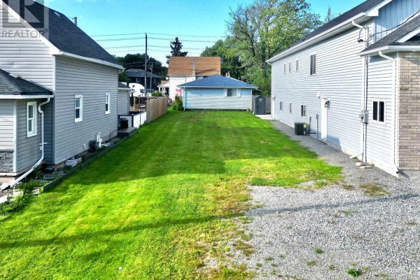 View of a grassy lot between two houses, with a gravel path on one side. - 44 Chestnut Street, Port Colborne