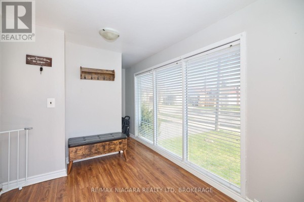 Interior entryway with wood-look flooring, bench, coat rack, and large window with blinds. - 44 Churchill Street, St  Catharines