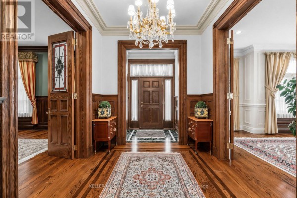 Grand foyer with dark wood trim, chandelier, and patterned area rugs. - 44 Cotswold Crescent, Toronto