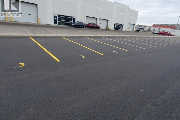 Asphalt parking lot with yellow painted numbered parking stalls in front of garage bay doors. - 44 Ditton Drive Unit# 3, Hamilton