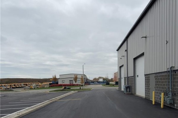 Commercial building with grey brick base and white corrugated metal upper section, showing large garage doors. - 44 Ditton Drive Unit# 3, Hamilton