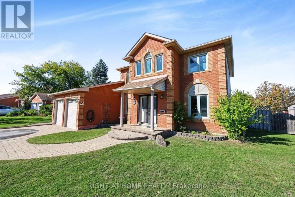 Side view of a brick house with a two-car garage and green lawn. - 44 Edenbridge Drive, Essa