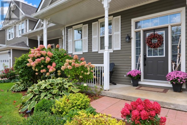 Close-up of the front entrance with a dark grey door, wreath, and pink and red hydrangeas. - 44 Green Briar Drive, Collingwood