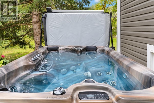Outdoor hot tub with grey cover open, showing blue water with jets. - 44 Green Briar Drive, Collingwood
