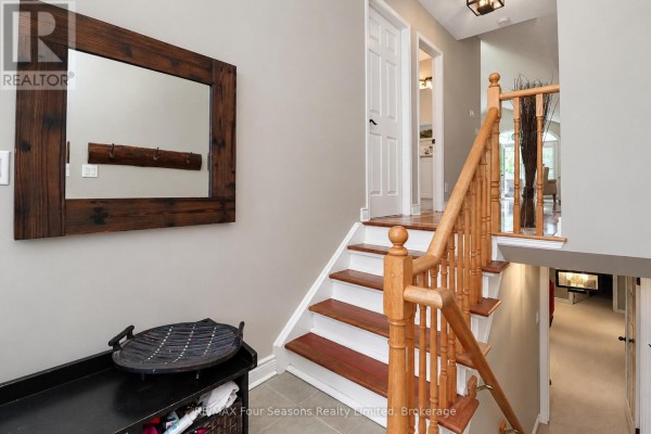 Interior hallway with a wooden staircase, mirror, bench, and doors leading to other rooms. - 44 Green Briar Drive, Collingwood