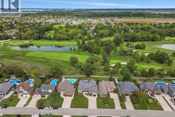 Aerial view looking down onto houses and a golf course with a pond and trees. - 44 Hilton Court, Amherstburg