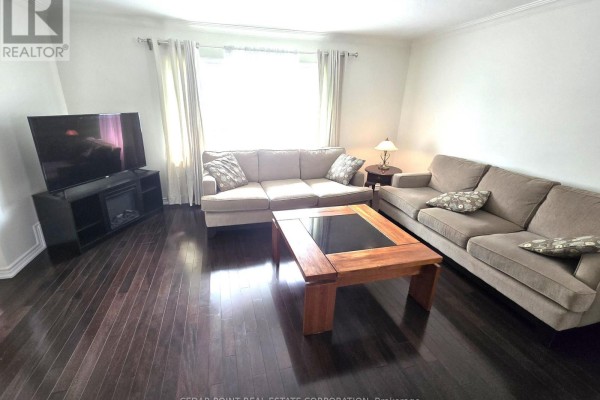 Living room with sectional sofa, coffee table, fireplace, and dark wood floors. - 44 Janet Boulevard, Toronto