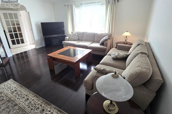 Living room with two sofas, coffee table, electric fireplace, and dark hardwood floors. - 44 Janet Boulevard, Toronto