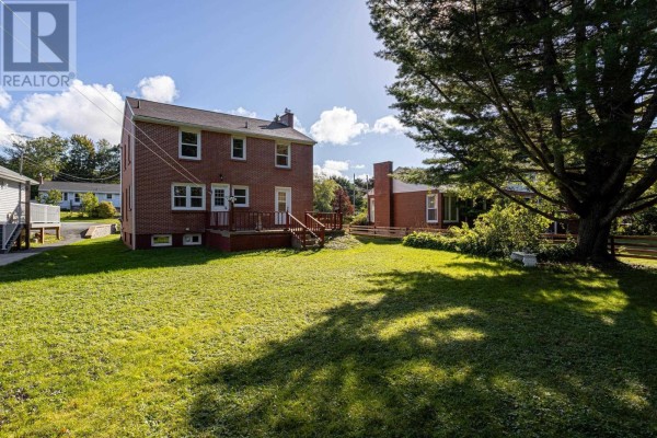 Rear exterior of the house with a brick chimney, green lawn, and large tree. - 44 Locks Road, Dartmouth