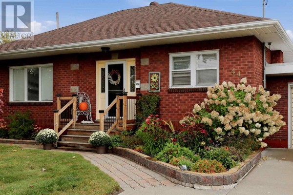 Close-up of the front entrance of a red brick house with a walkway and garden. - 44 Mccrea St, Sault Ste  Marie