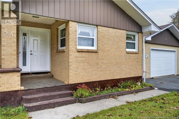 Close-up of the front entrance of the house, showing a white door, beige brick, and a concrete walkway. - 44 Nelson Street, Miramichi