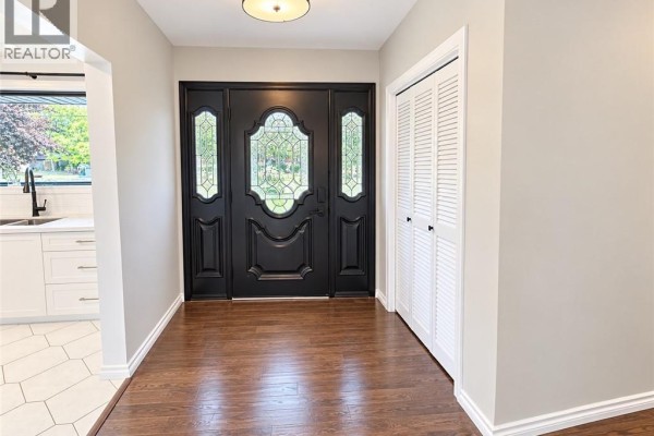 Entrance foyer with dark wood floor and white bi-fold closet doors. - 44 Patterson Avenue Unit# A, Brantford