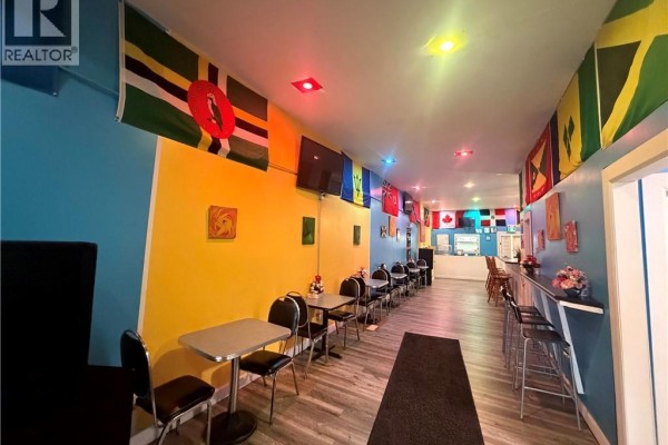 Restaurant interior showing tables, chairs, a counter, and flags from various nations on yellow walls. - 44 Robinson Street, Simcoe