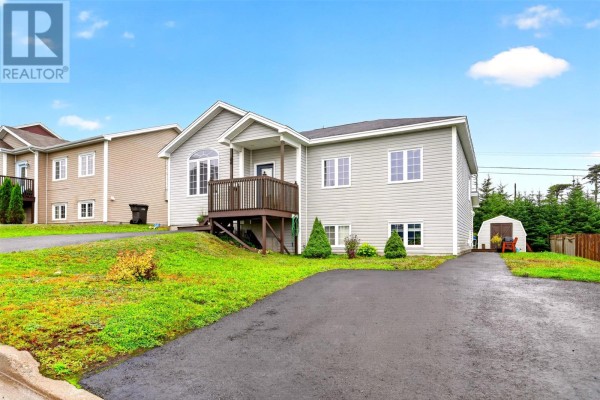 Front exterior view of a grey split-level house with a dark wood deck and railing and a shed. - 44 Seascape Drive, Paradise