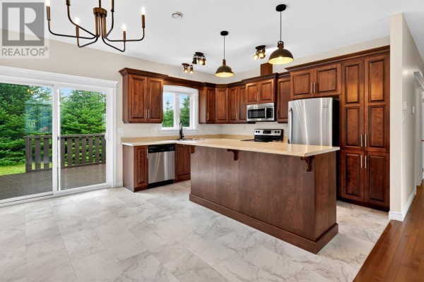 Modern kitchen with dark wood cabinets, granite countertops, stainless steel appliances, and large island. - 44 Seascape Drive, Paradise