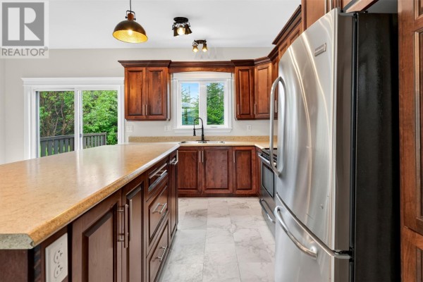Kitchen with dark wood cabinets, granite countertops, stainless steel refrigerator, and light grey tiled floor. - 44 Seascape Drive, Paradise