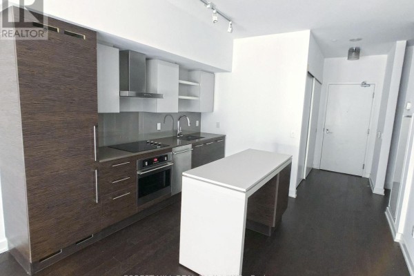 Contemporary kitchen with stainless steel appliances, grey backsplash, and white island. - 440 - 1030 King Street W, Toronto