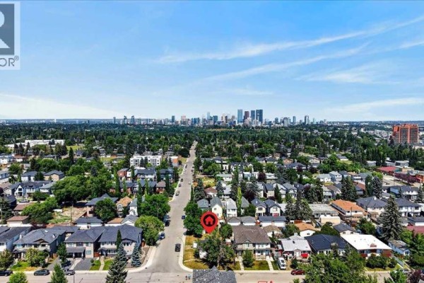 Aerial view of a suburban neighborhood with a downtown skyline in the distance. - 440 53 Avenue Sw, Calgary