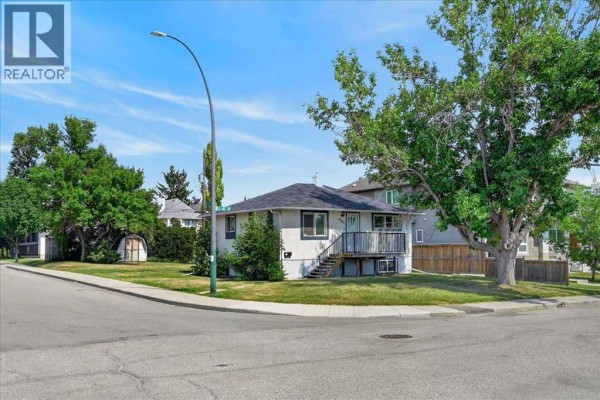 Front view of a single-family house with light stucco exterior and wooden steps. - 440 53 Avenue Sw, Calgary