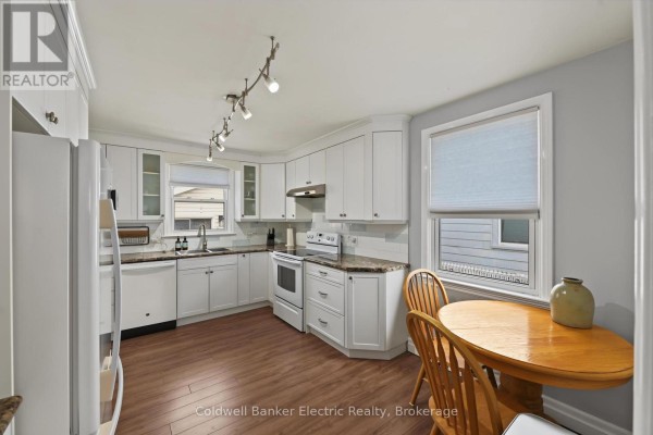Kitchen with white cabinets, granite counters, and a breakfast nook with a wooden table and chairs. - 440 Howden Street, Peterborough