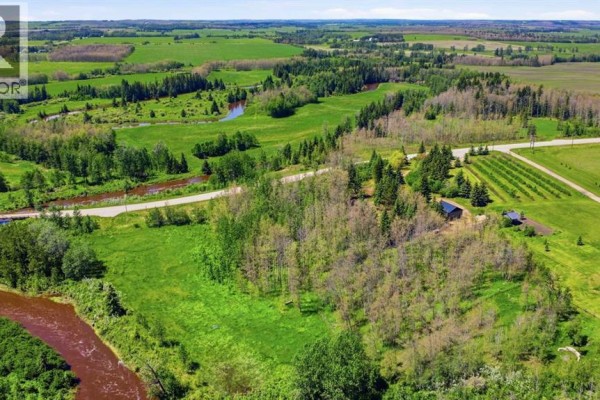 Drone view of wooded land with buildings, fields, and a winding creek on the right. - 440029 Range Road 30, Rural Ponoka County
