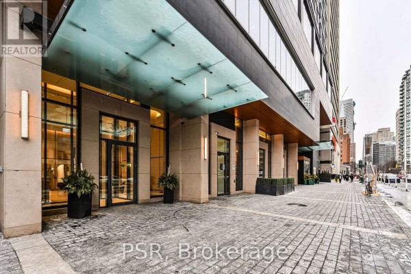 Entrance to a modern building with a glass canopy and stone facade. - 4409 - 395 Bloor Street E, Toronto