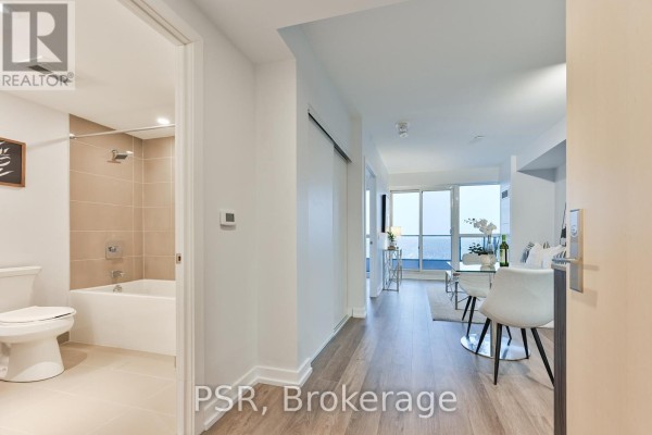 View from apartment entrance showing bathroom with beige tiles and open living area. - 4409 - 395 Bloor Street E, Toronto