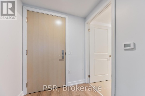 Hallway of an apartment with a light wood door and light grey walls. - 4409 - 395 Bloor Street E, Toronto