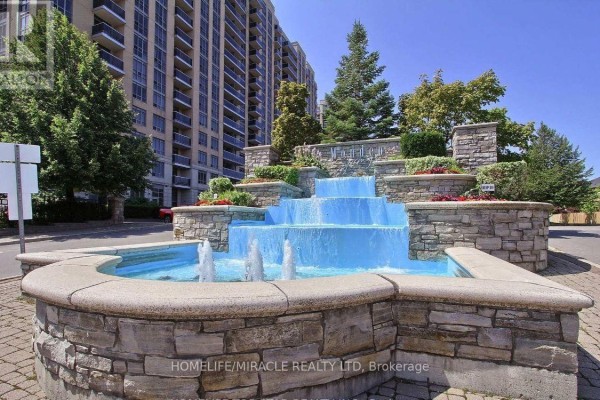 Close-up of a multi-tiered stone fountain with bright blue water and jets spraying into the air. - 441 - 18 Mondeo Drive, Toronto