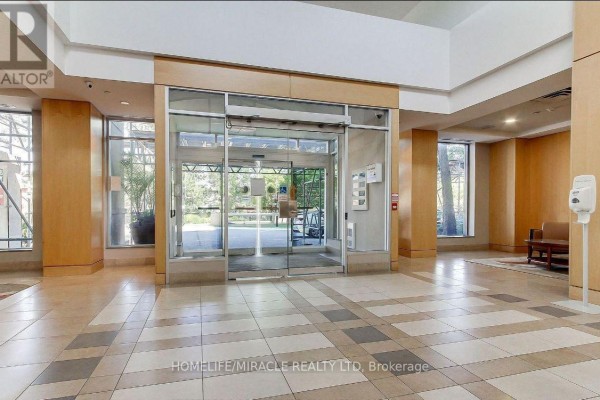 Interior view of a building lobby with double glass doors, beige tiled floor, and wood-paneled walls. - 441 - 18 Mondeo Drive, Toronto