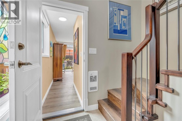 Home office with light wood floors, two bookshelves, and a desk with chairs. - 442 Alexander Ave Avenue Unit# 201, Penticton